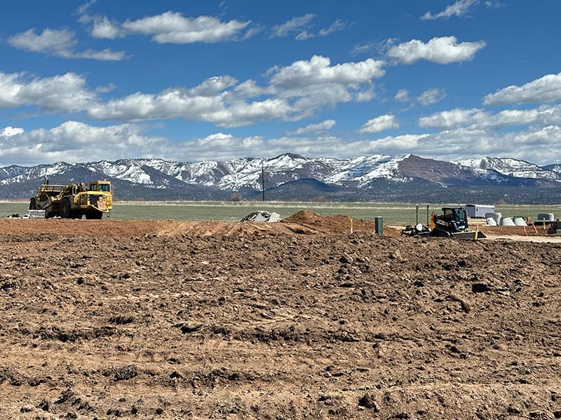 Tractor working a lot at Mustang Crossing with mountain views